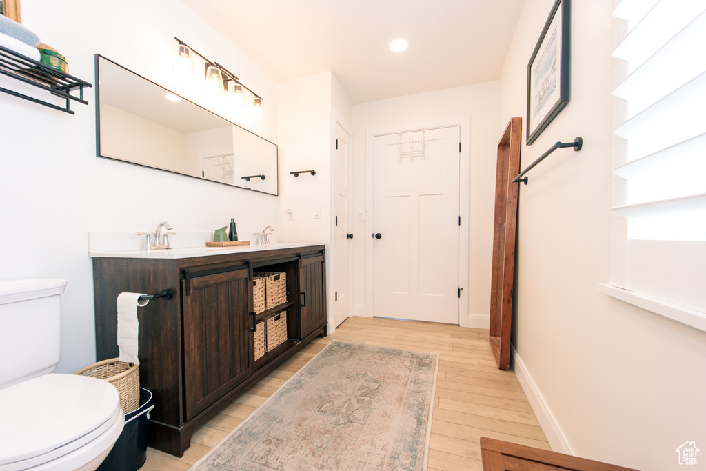 Bathroom with wood finished floors, double vanity, and recessed lighting