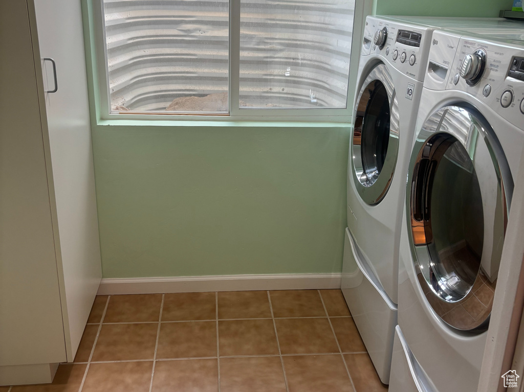 Laundry room with washing machine and dryer and light tile patterned floors