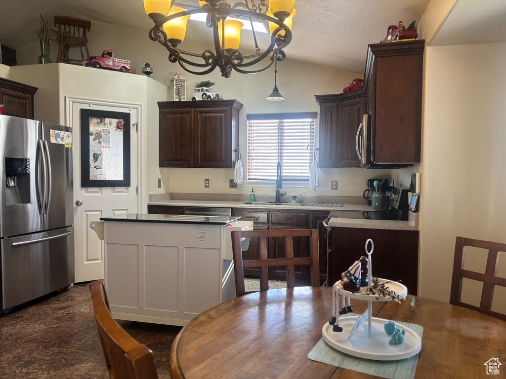 Kitchen featuring appliances with stainless steel finishes, a chandelier, vaulted ceiling, dark brown cabinets, and decorative light fixtures