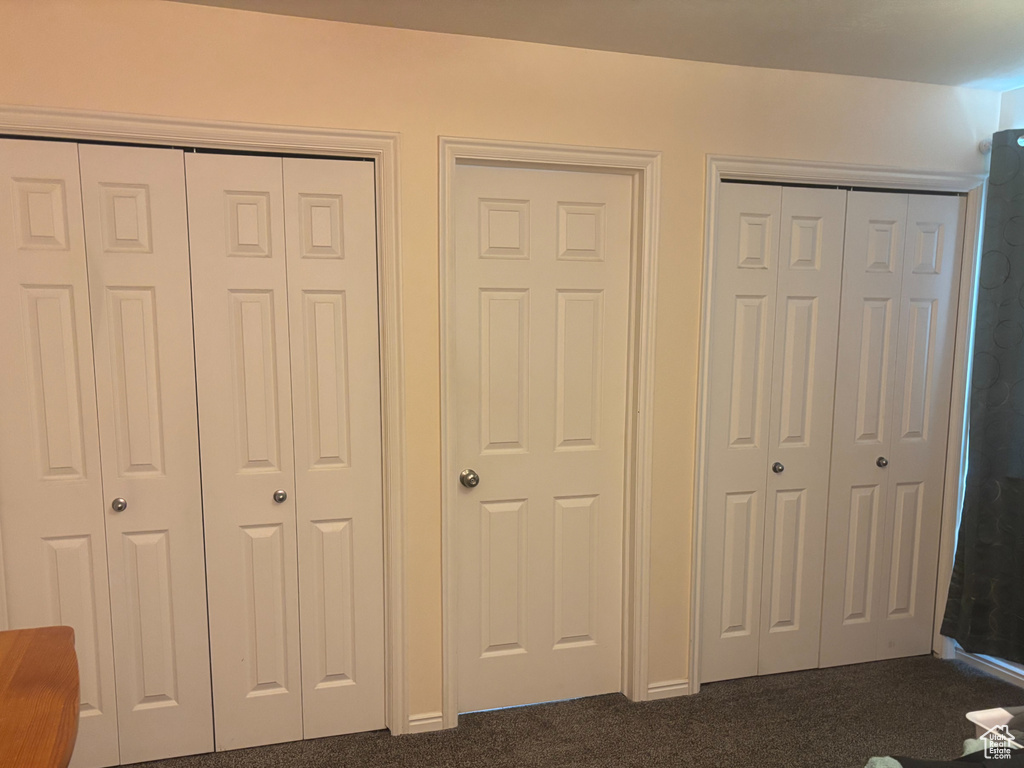 Bedroom featuring dark colored carpet and multiple closets