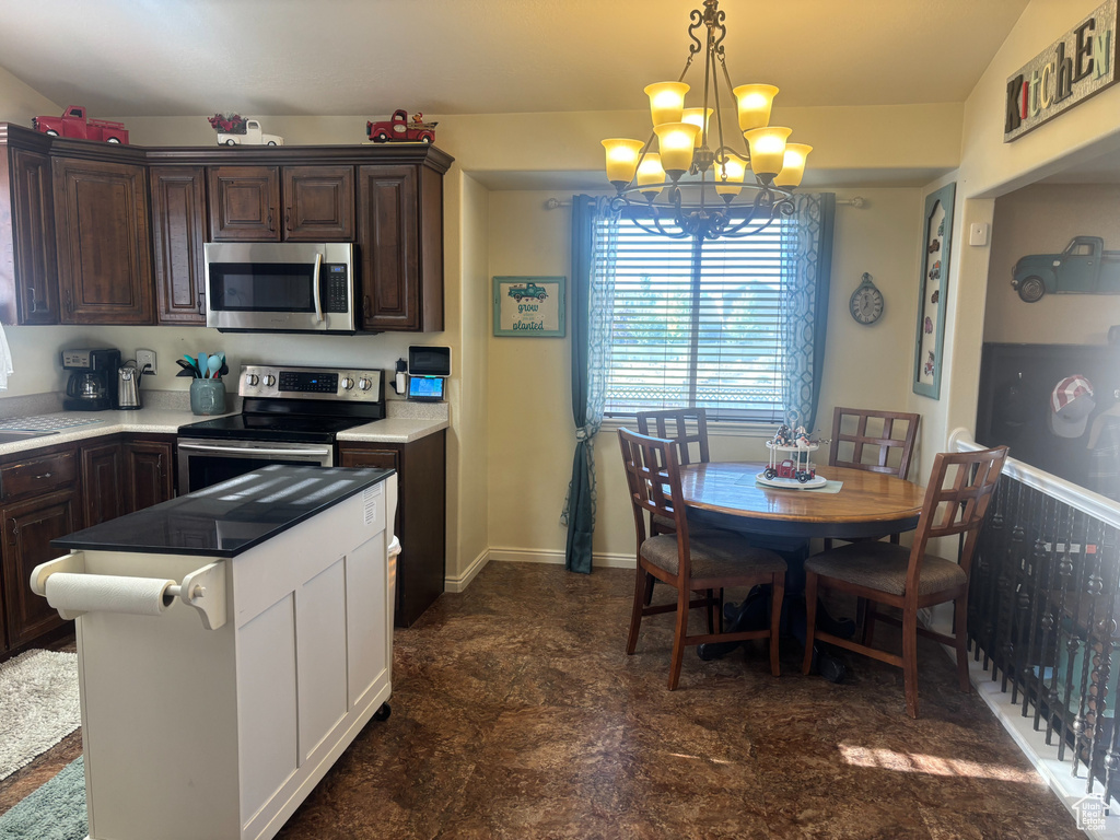 Kitchen with appliances with stainless steel finishes, a chandelier, dark brown cabinets, and light countertops