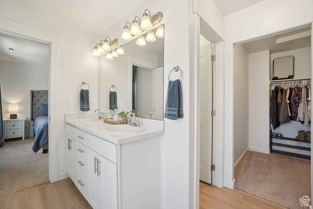 Ensuite bathroom with double vanity, wood finished floors, and a walk in closet