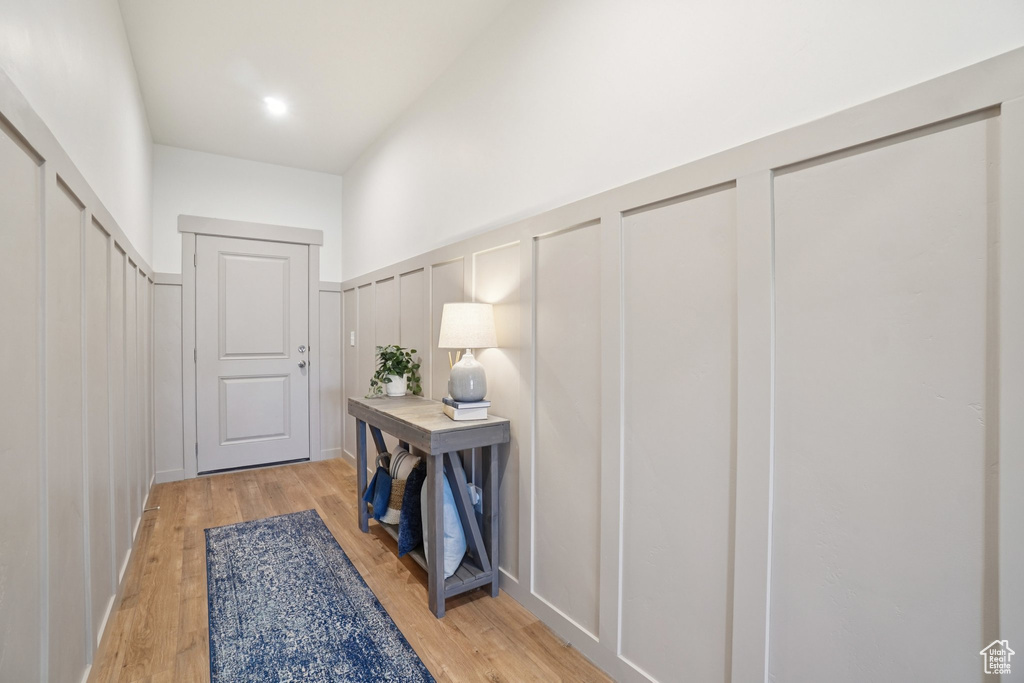 Doorway with a decorative wall, light wood-type flooring, and a wainscoted wall
