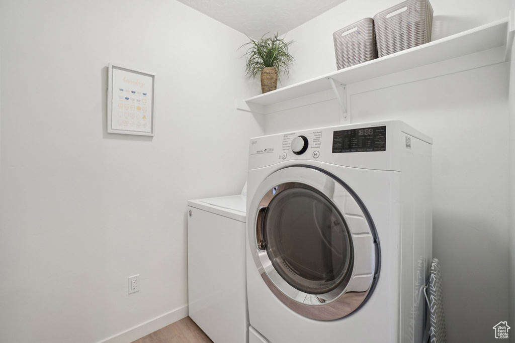 Laundry area with washer and clothes dryer and light wood finished floors