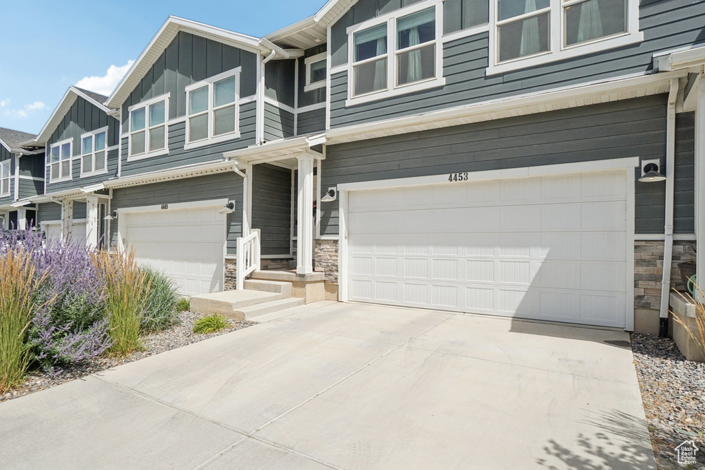 Craftsman house featuring stone siding, a garage, concrete driveway, and board and batten siding