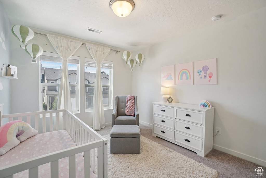 Bedroom with light colored carpet and a nursery area