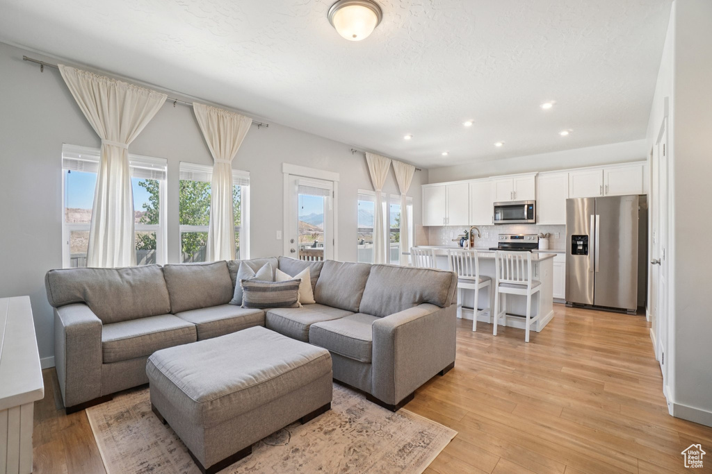 Living room with light wood-style flooring and recessed lighting