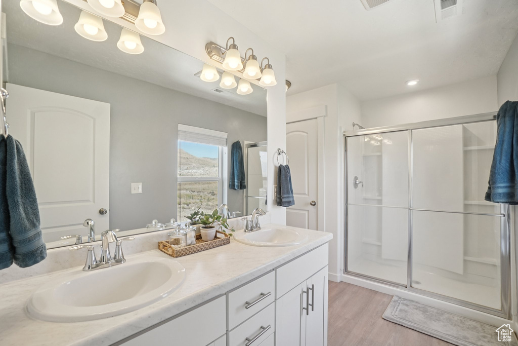 Full bathroom with wood finished floors, double vanity, and a shower stall