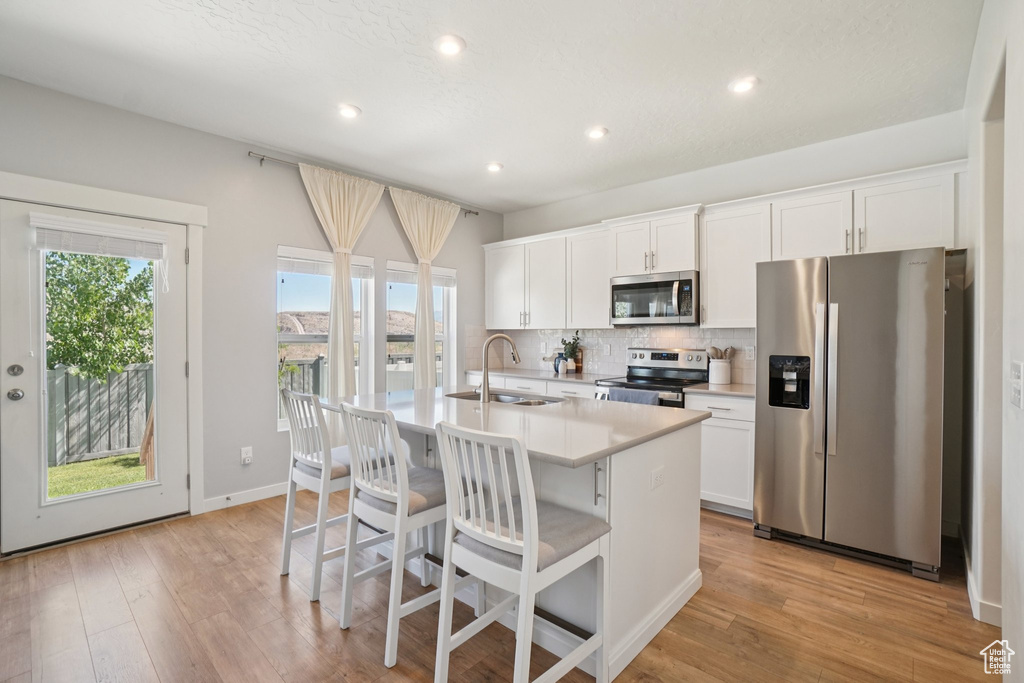 Kitchen featuring stainless steel appliances, a center island with sink, plenty of natural light, a breakfast bar area, and recessed lighting