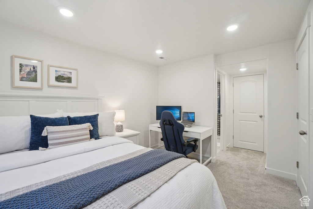 Bedroom with light carpet, recessed lighting, and a desk