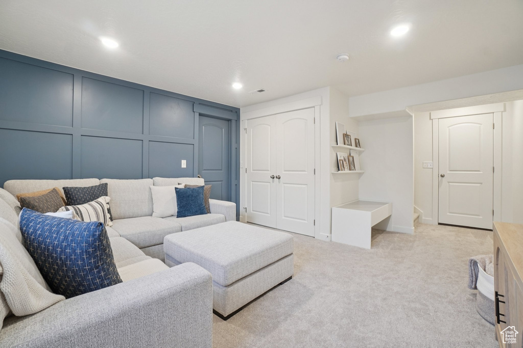 Living room featuring a decorative wall, light carpet, and recessed lighting