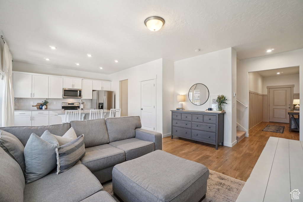 Living room with light wood-type flooring, stairway, and recessed lighting