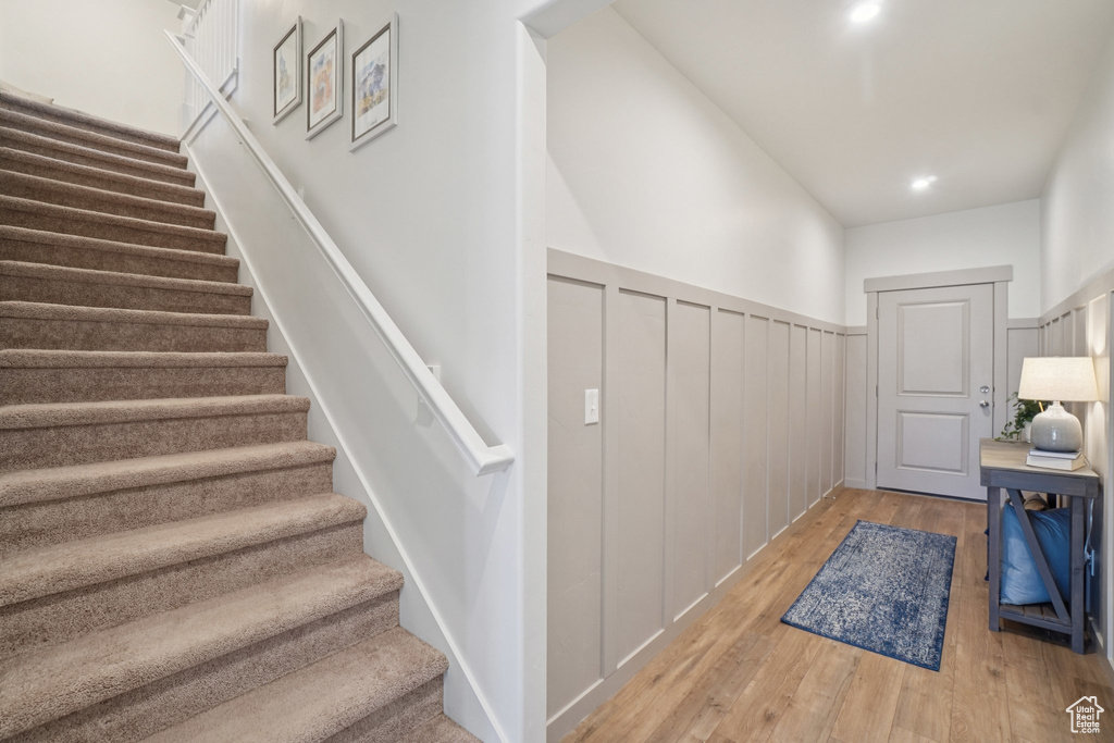 Staircase featuring wainscoting, wood-type flooring, and a decorative wall