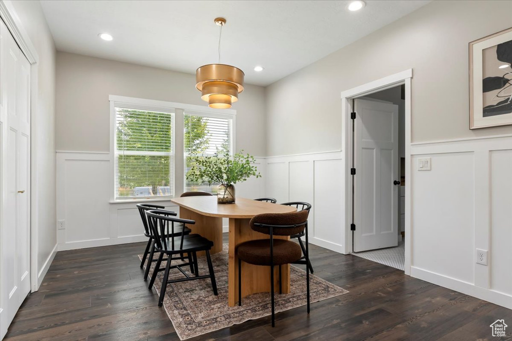 Dining space with a decorative wall, wainscoting, dark wood-style floors, and recessed lighting