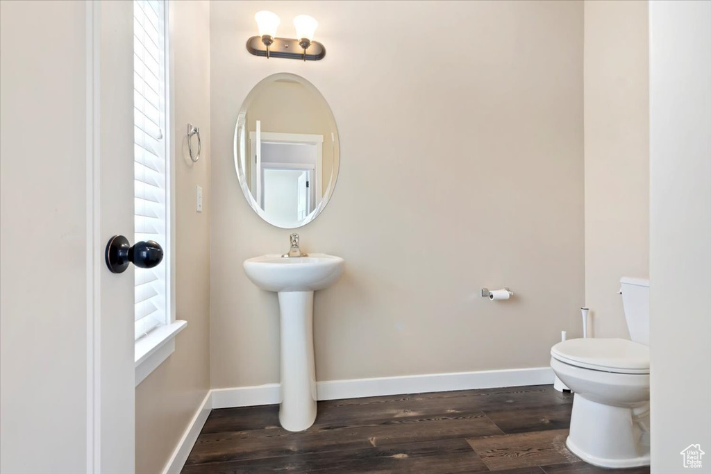 Half bathroom with toilet and wood finished floors