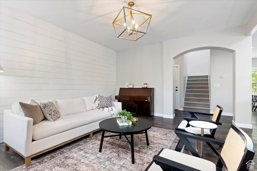 Living area featuring arched walkways, dark wood-style flooring, stairs, and a chandelier