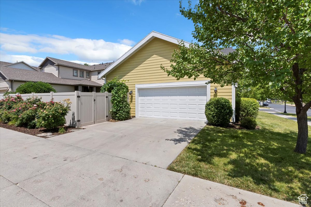 View of side of home featuring a gate, a garage, and driveway