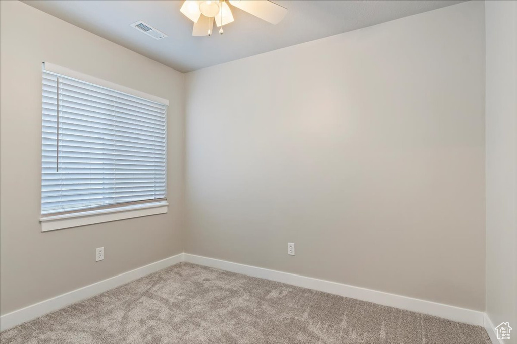 Carpeted spare room with ceiling fan and baseboards