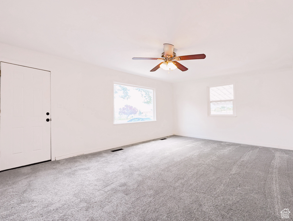 Empty room with a ceiling fan and carpet flooring