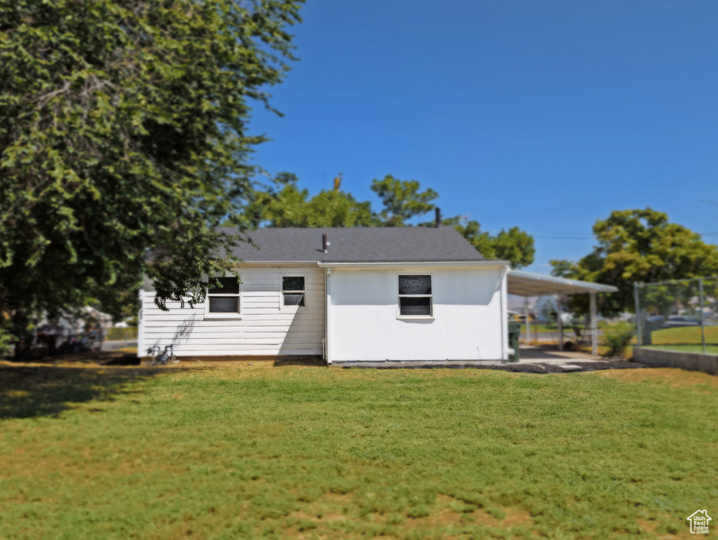 Rear view of house featuring a lawn and an attached carport