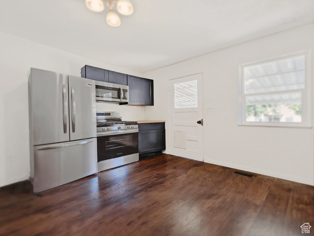 Kitchen featuring appliances with stainless steel finishes, dark wood finished floors, and light countertops