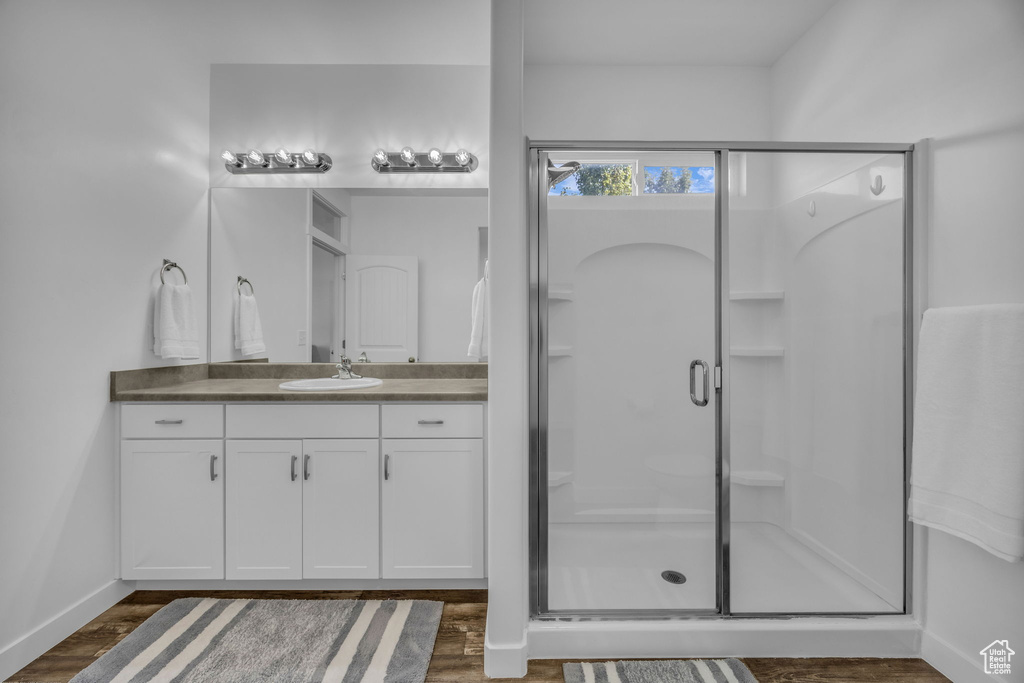 Full bathroom featuring a stall shower, vanity, and wood finished floors