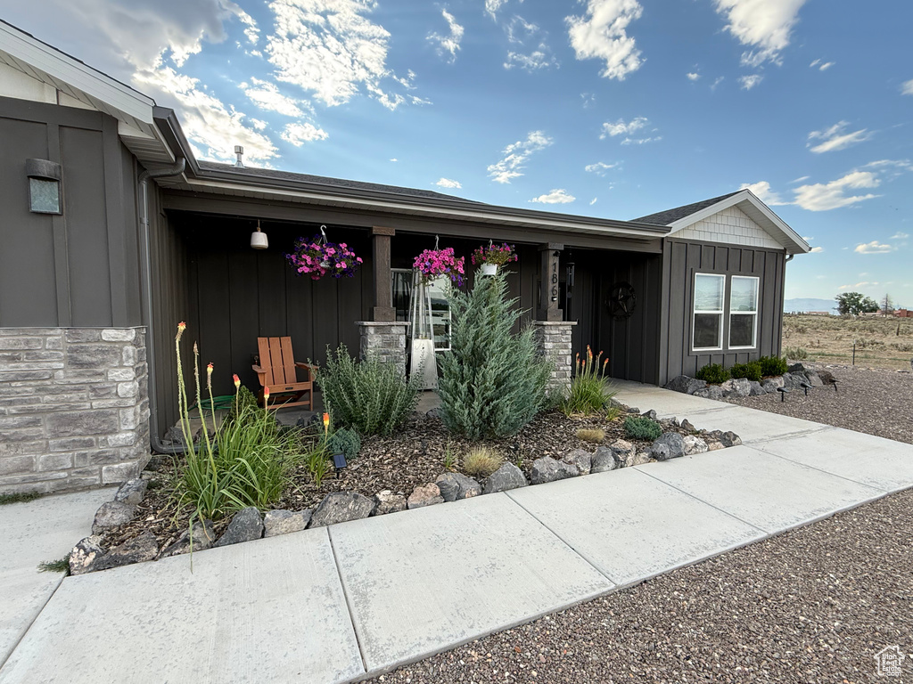 View of front of home featuring board and batten siding, covered porch, and stone siding