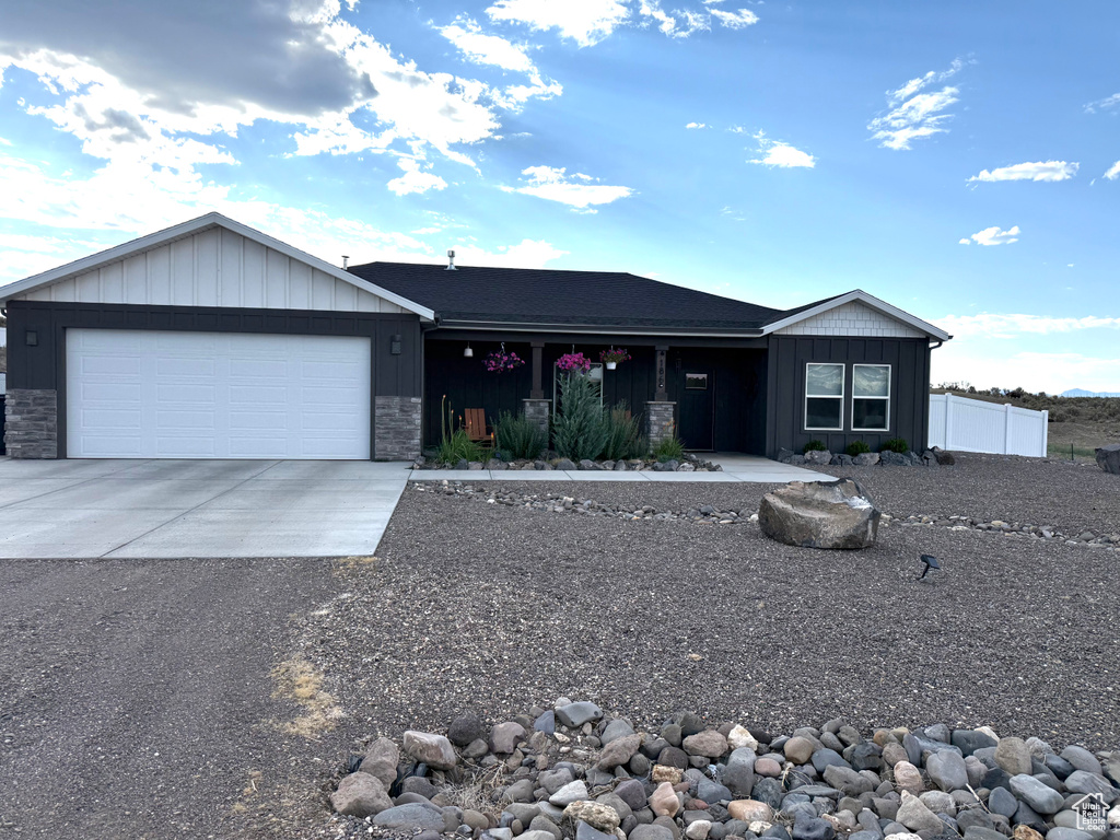 Ranch-style home with driveway, board and batten siding, a garage, and stone siding