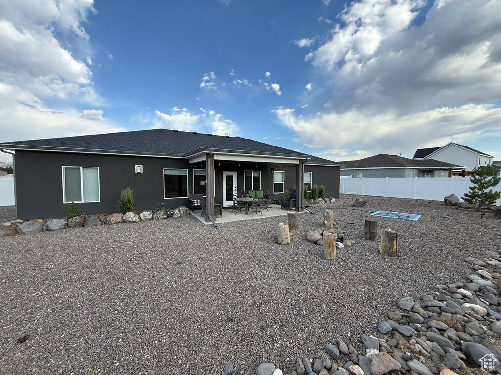 Rear view of property with stucco siding, a patio area, and a shingled roof
