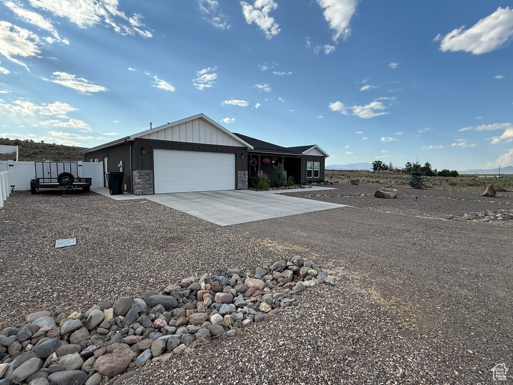 View of side of home featuring concrete driveway, an attached garage, board and batten siding, and stone siding