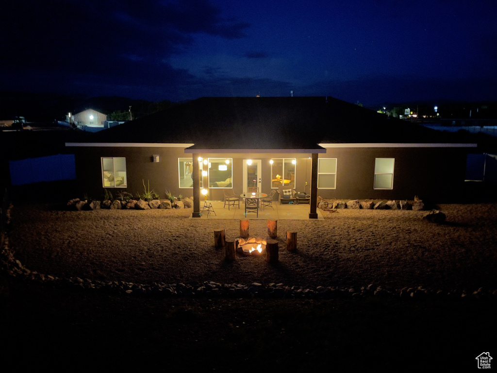 Back of house at twilight with stucco siding and a patio