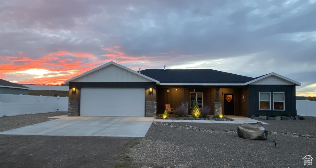 Ranch-style house with stone siding, concrete driveway, a garage, a porch, and board and batten siding