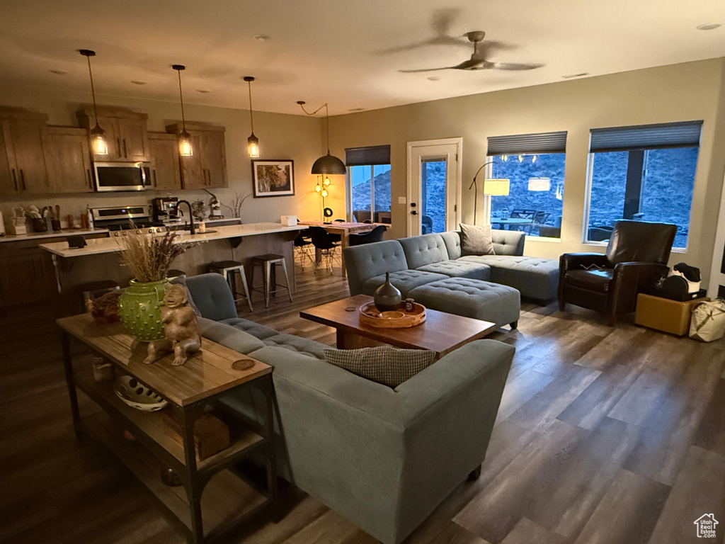Living area with dark wood-style floors and a ceiling fan