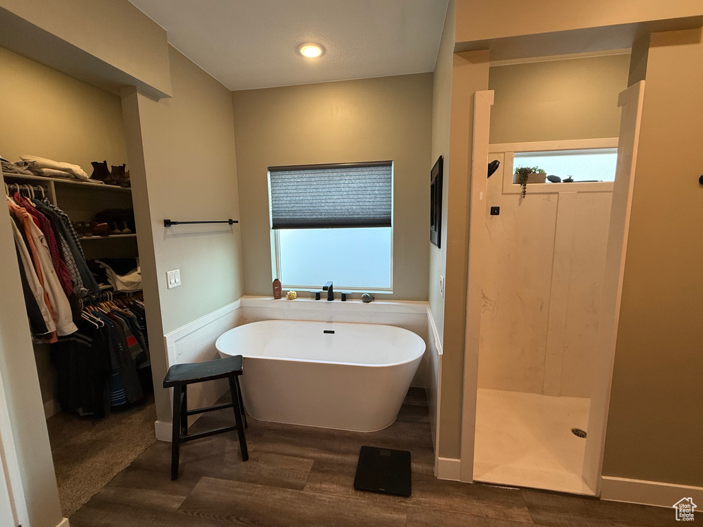 Bathroom with a soaking tub, a spacious closet, walk in shower, wood finished floors, and recessed lighting
