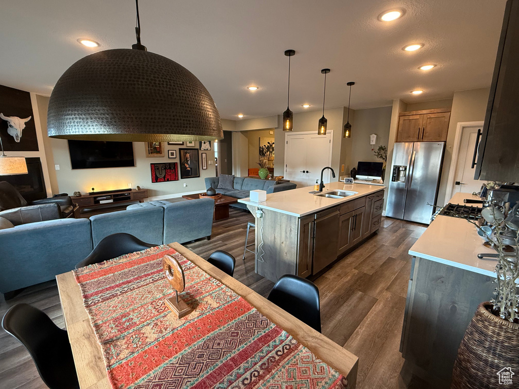 Kitchen featuring open floor plan, stainless steel appliances, light countertops, pendant lighting, and recessed lighting