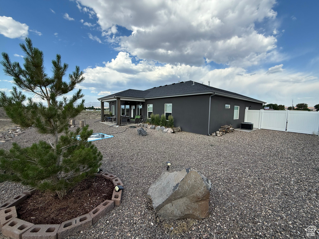 Rear view of property with stucco siding, a gate, and a patio area