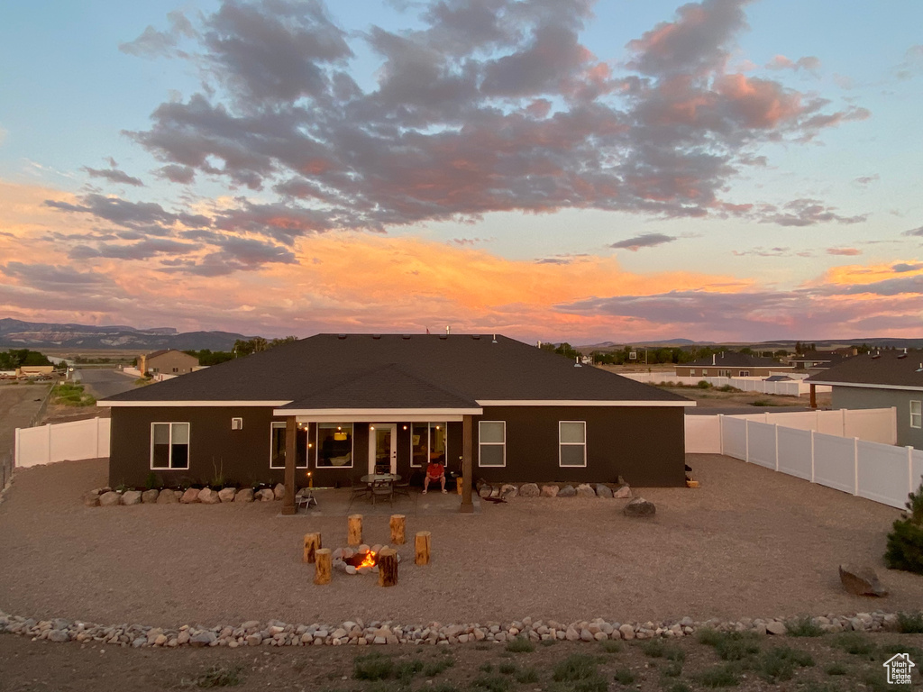 Back of property at dusk featuring a patio area, stucco siding, a fenced backyard, and an outdoor fire pit