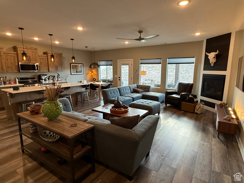 Living area with a ceiling fan, recessed lighting, dark wood-type flooring, and a glass covered fireplace