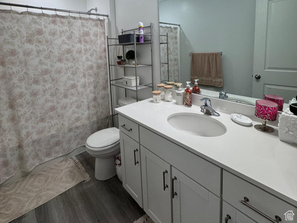 Full bathroom featuring wood finished floors, vanity, and curtained shower
