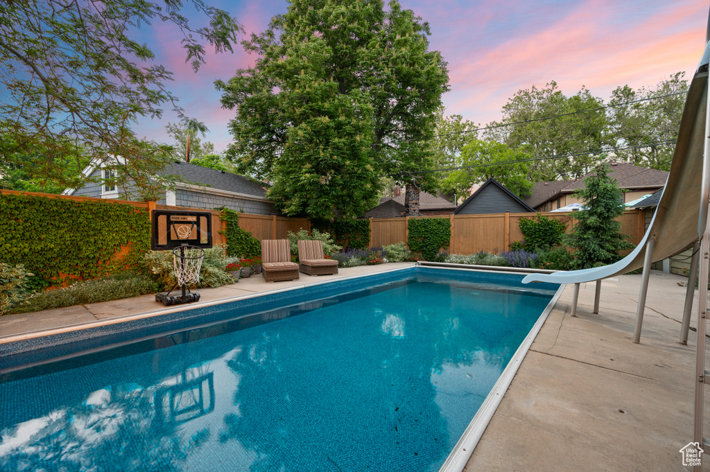 View of swimming pool featuring a water slide, a fenced backyard, and a patio