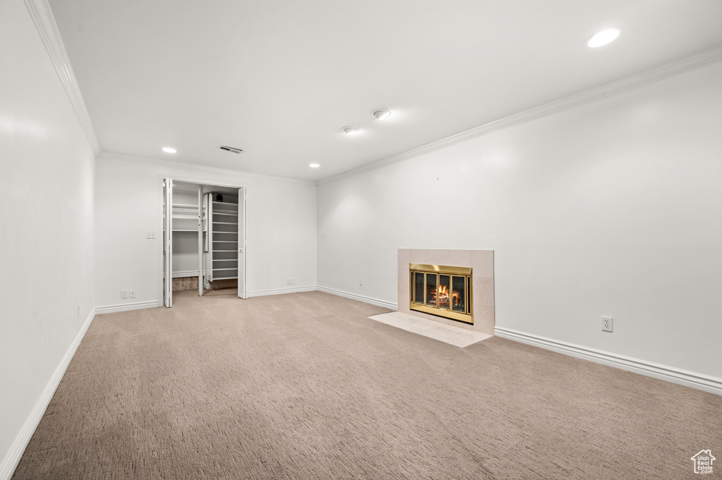 Unfurnished living room featuring ornamental molding, recessed lighting, light carpet, and a tiled fireplace