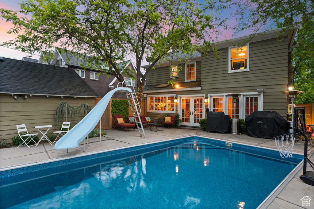 View of swimming pool with french doors, a water slide, a patio area, and a grill