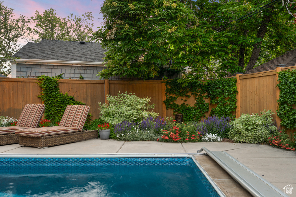 Pool at dusk featuring a fenced backyard and a patio area