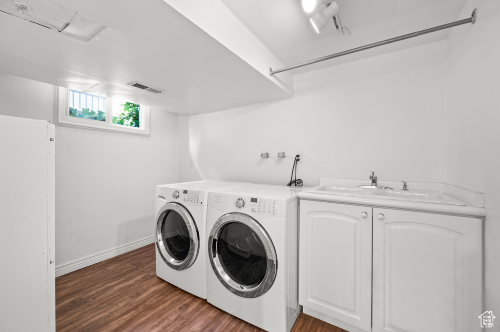 Laundry room with cabinet space, washing machine and dryer, and wood finished floors