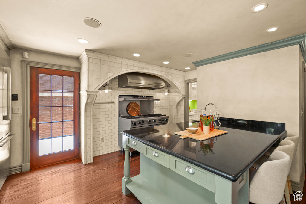 Kitchen featuring dark wood-type flooring, green cabinets, recessed lighting, dark countertops, and range hood