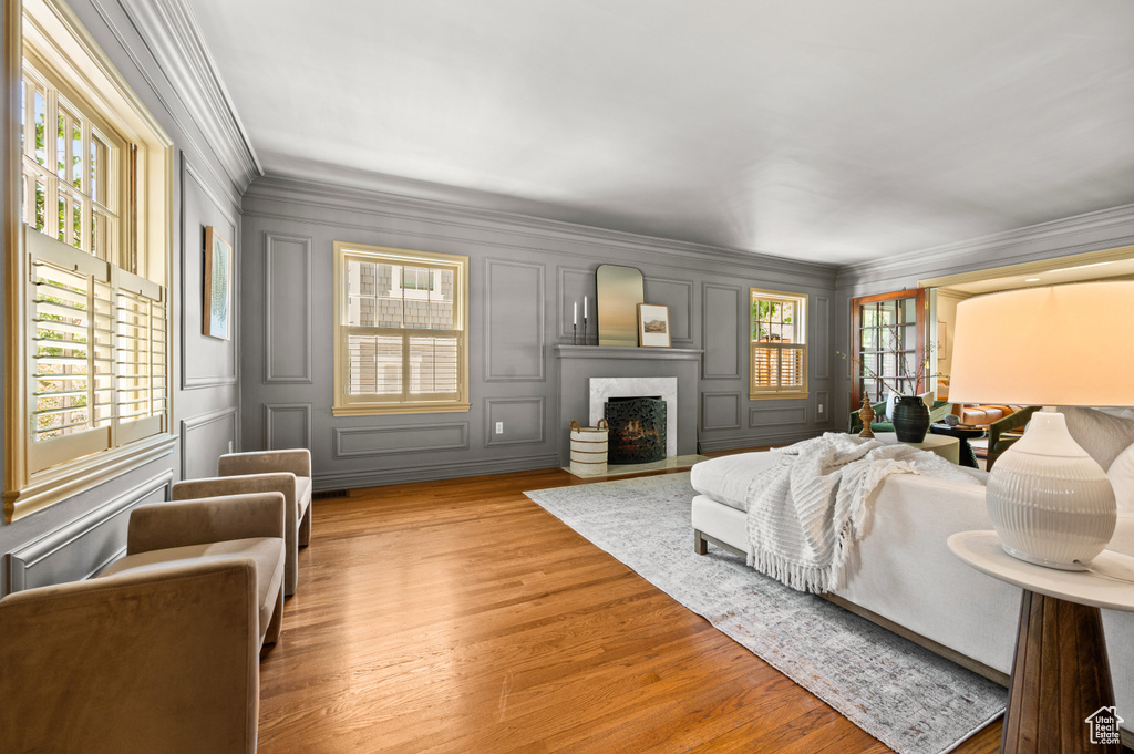 Living room with a high end fireplace, a decorative wall, crown molding, and wood finished floors