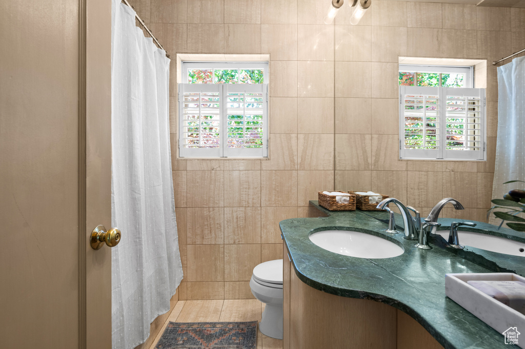 Full bath with tile walls, vanity, and a shower with curtain