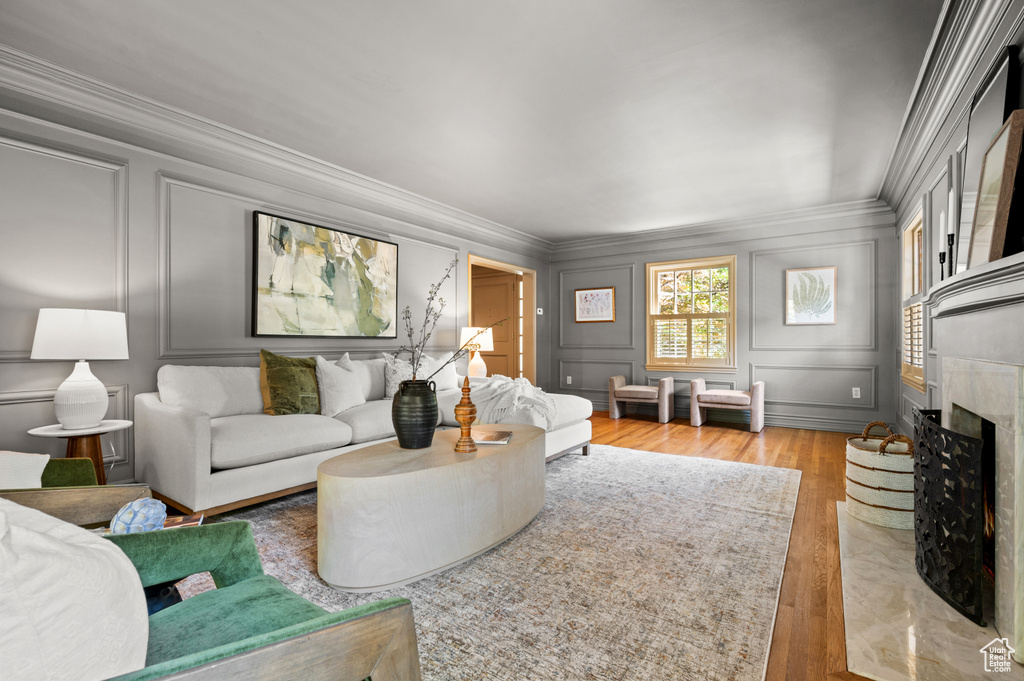 Living room with a decorative wall, ornamental molding, light wood finished floors, and a premium fireplace