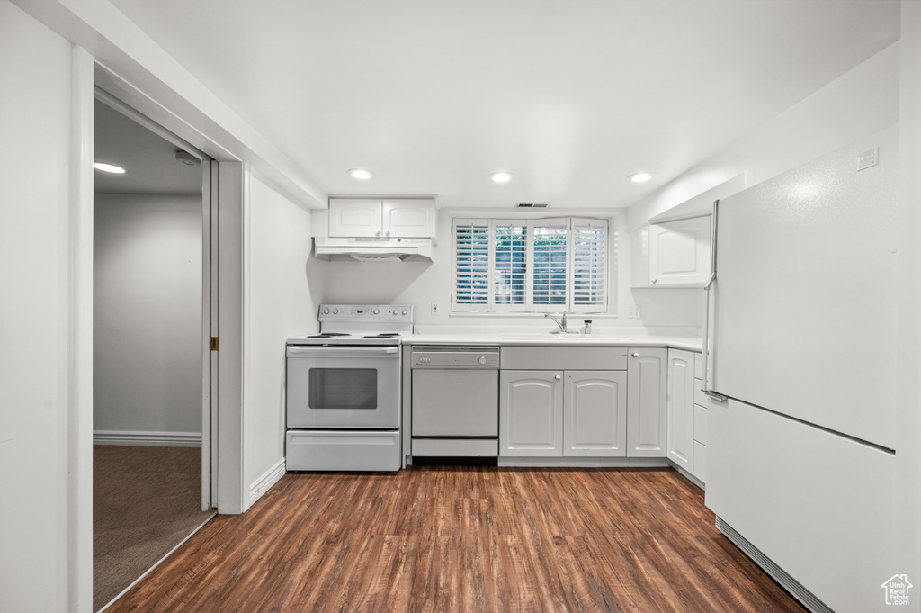 Kitchen with white appliances, dark wood-style floors, white cabinets, light countertops, and recessed lighting