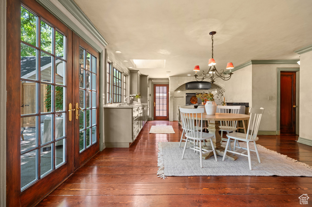 Dining space featuring a chandelier, dark wood-style flooring, ornamental molding, and french doors